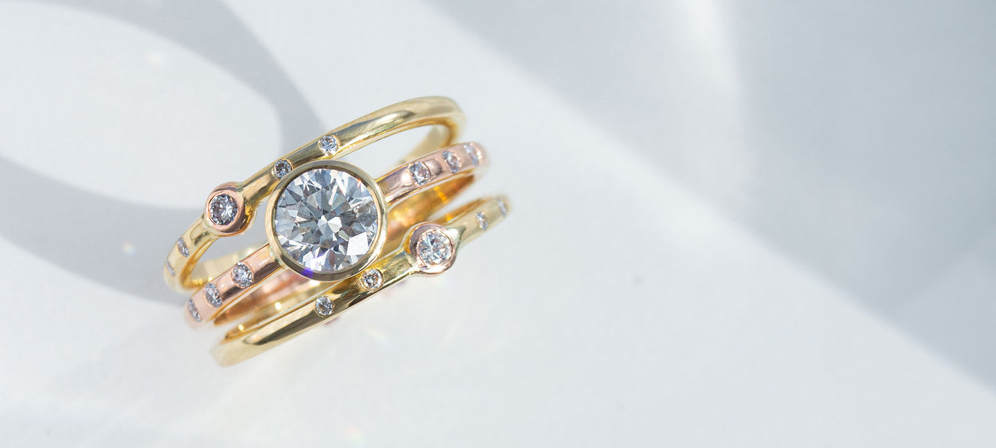 Triple Band Diamond ring with mixed yellow and rose gold standing with white background
