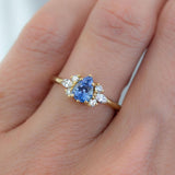 Pear blue sapphire cluster ring with round and marquise shape white diamonds in 18K yellow gold on hand by Amy Jennifer Jewellery