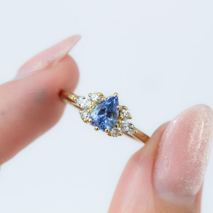 Pear blue sapphire cluster ring with round and marquise shape white diamonds in 18K yellow gold by Amy Jennifer Jewellery