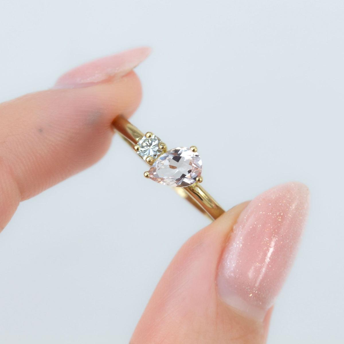 'Toi Et Moi' Ring - Pear shape Peach Morganite & Diamond Ring held between fingers